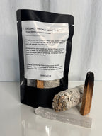 zu sehen ist einer verpackung, mit Palo Santo holz, Salbei und selenit Kristall davor, auf der verpackung steht ein mantra