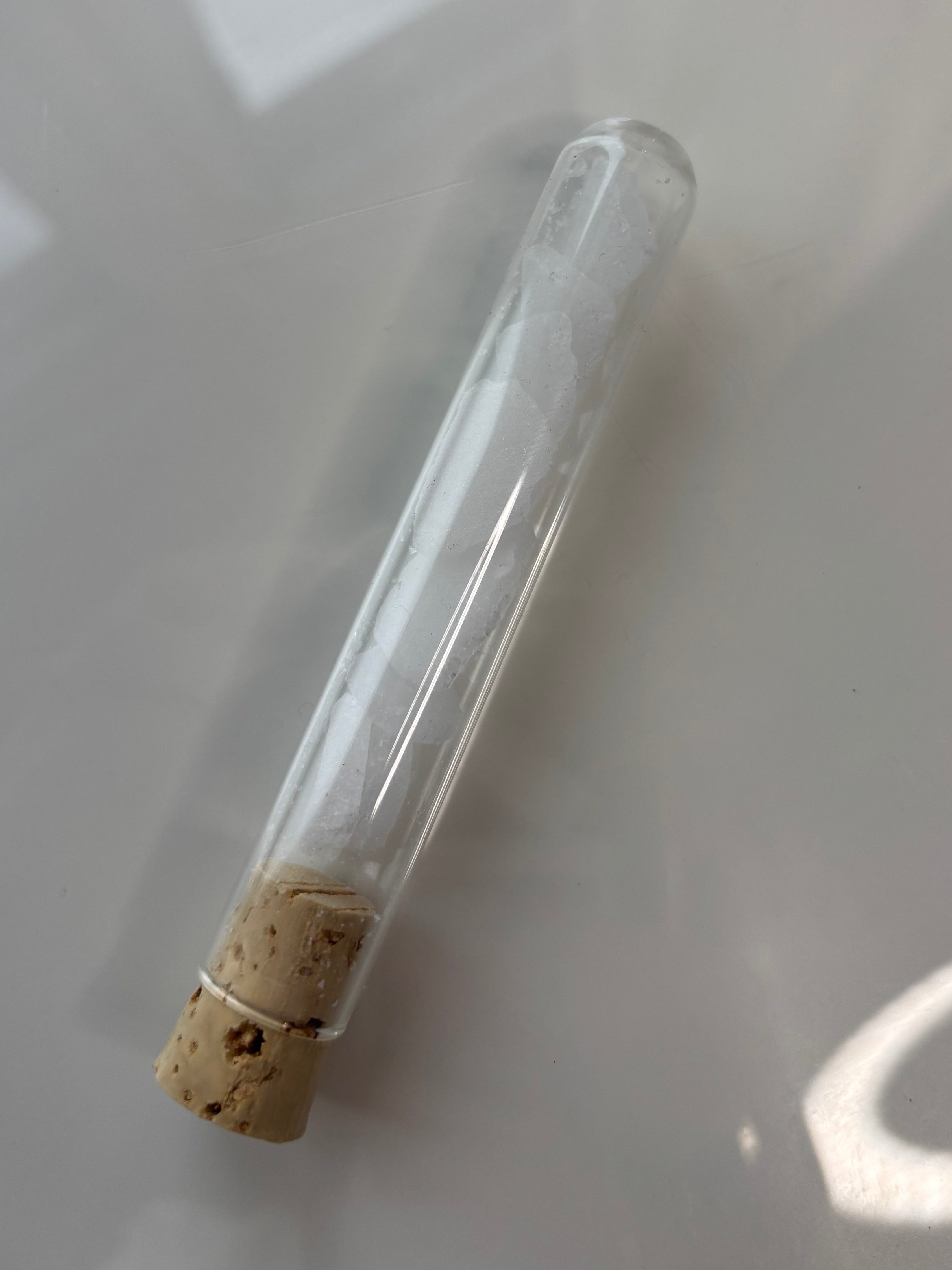 Packshot, Kampfer auf glänzendem Hintergrund in Glasröhrchen mit Korkverschluss